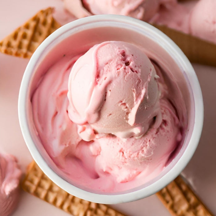 Pink ice cream in a white bowl with waffle cookies on a pink background
